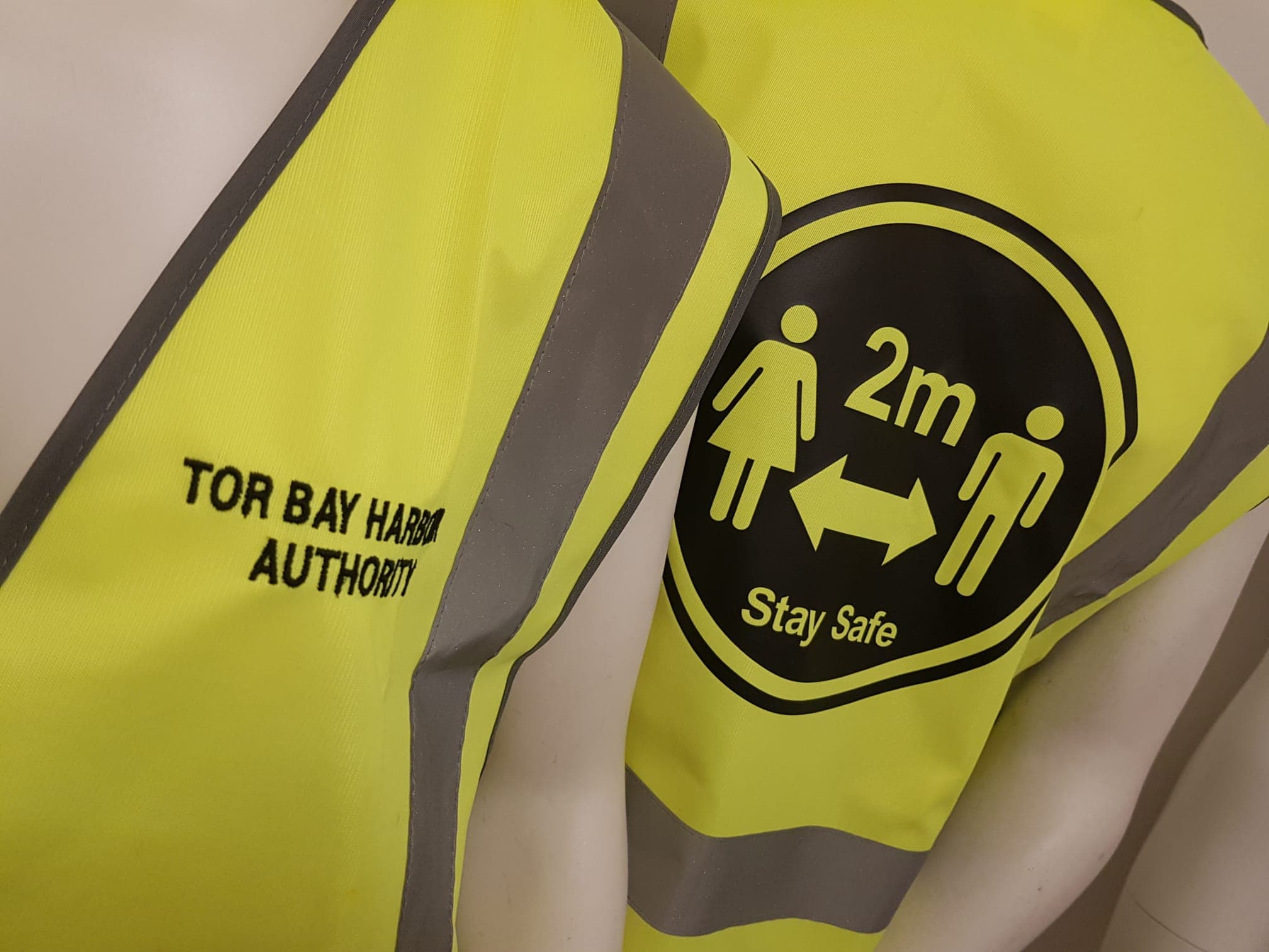Branded hi-vis safety vests printed with a logo and a 'Stay Safe' graphic