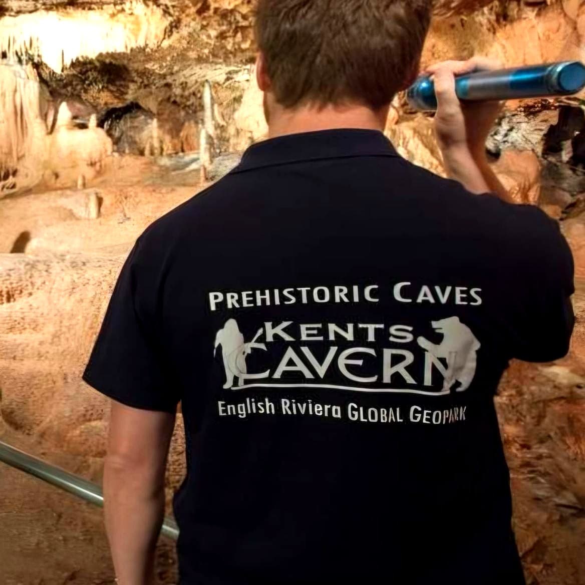 Black polo shirt screen-printed with the Kents Cavern Prehistoric Caves logo, worn inside the caves